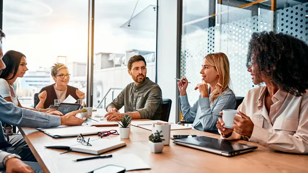 Business concept. Multinational professionals business people discussing daily topics by table in modern office. Business meeting.