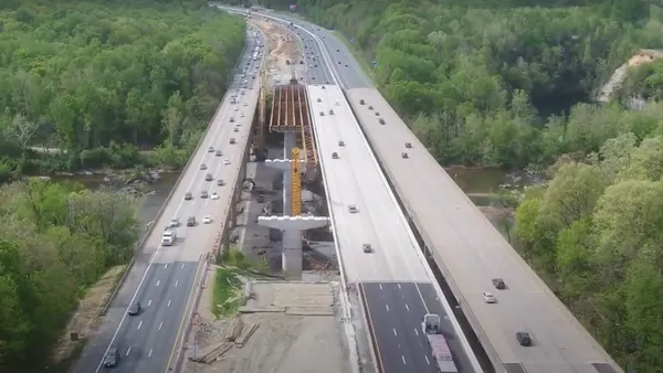 Aerial view of multilane highway surrounded by trees crossing over a river.