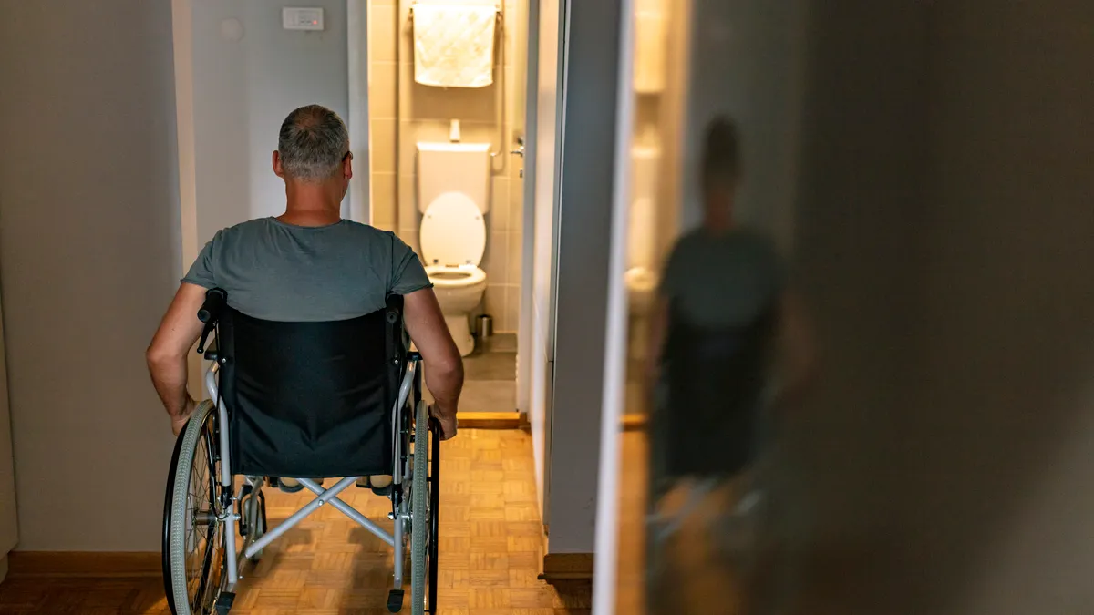 Man on wheelchair going to the toilet not adapted for disability person.