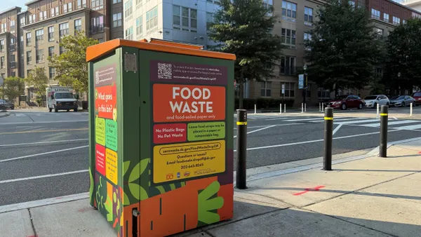An automated metal food waste bin sits on the side of the road