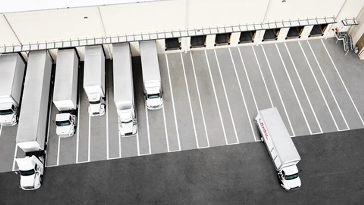 An overhead view shows trucks at a facility.