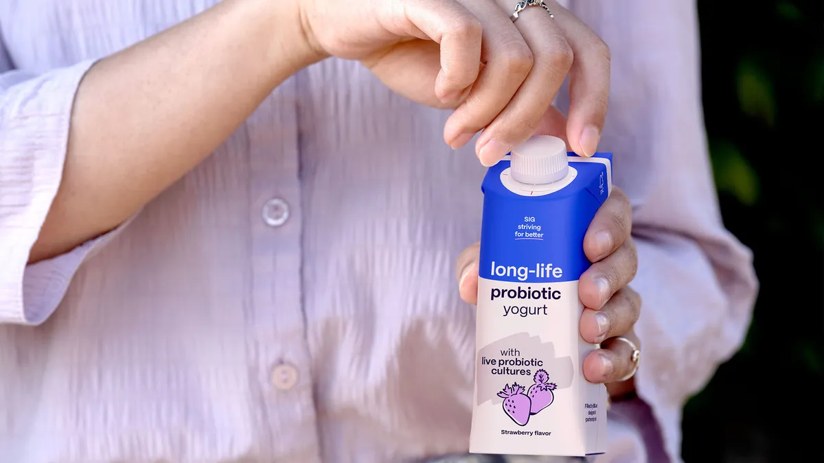 Person opening a plastic twist cap on a carton of probiotic yogurt.