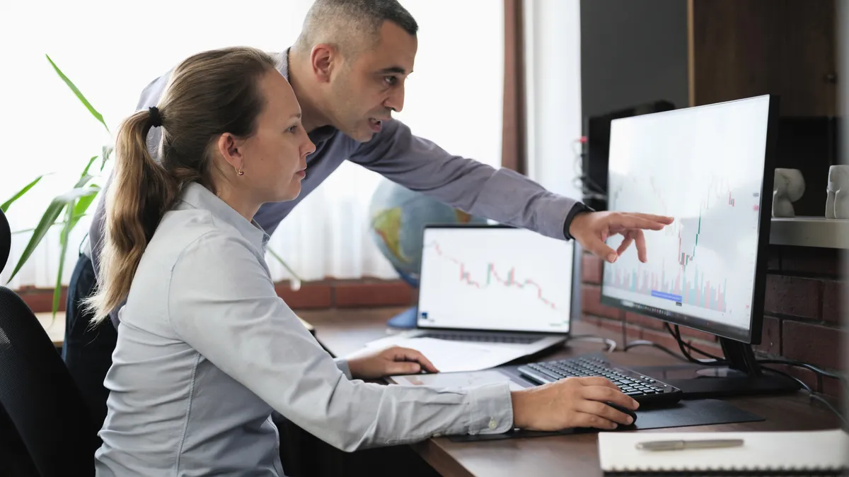 Businesspeople working in the office on stock market exchange data using desktop computer and digital tablet