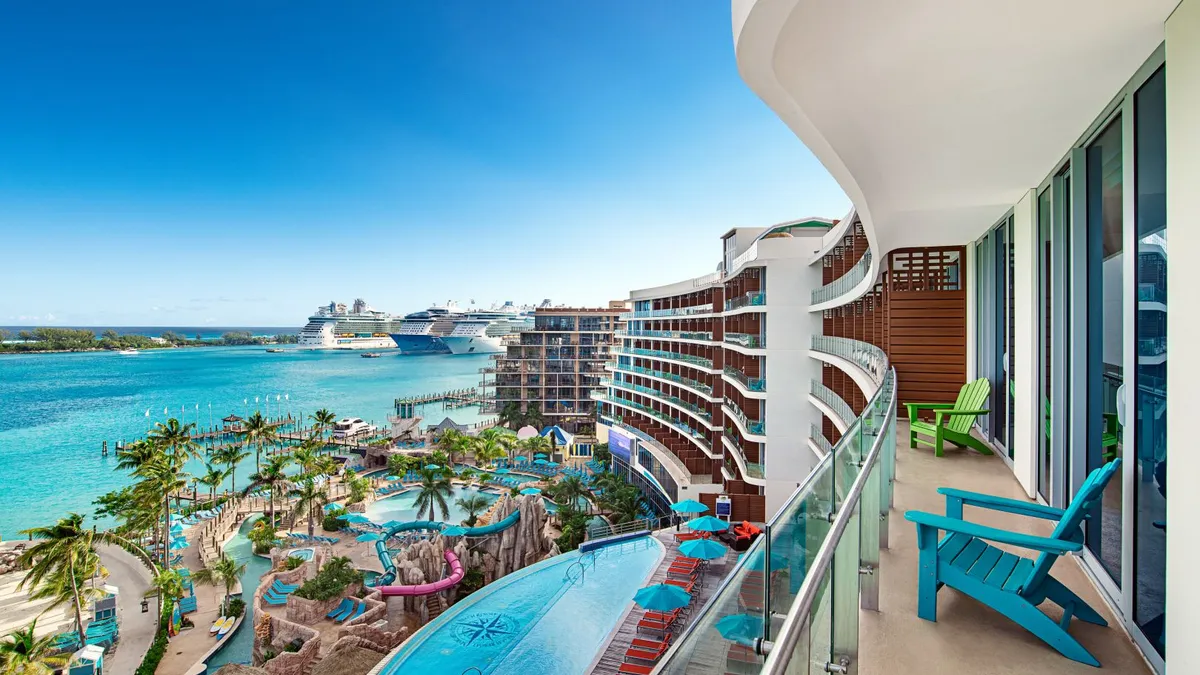 A balcony shows a view of a pool and ocean.