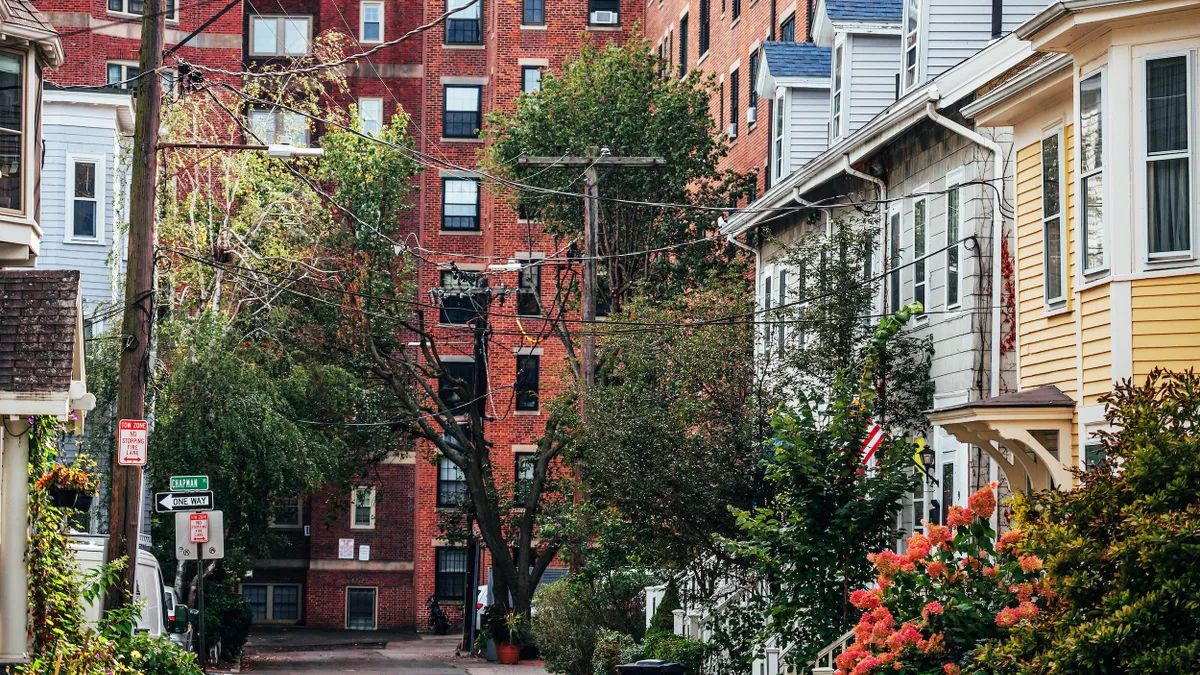 Wood row homes amid tightly packed taller brick apartment buildings.