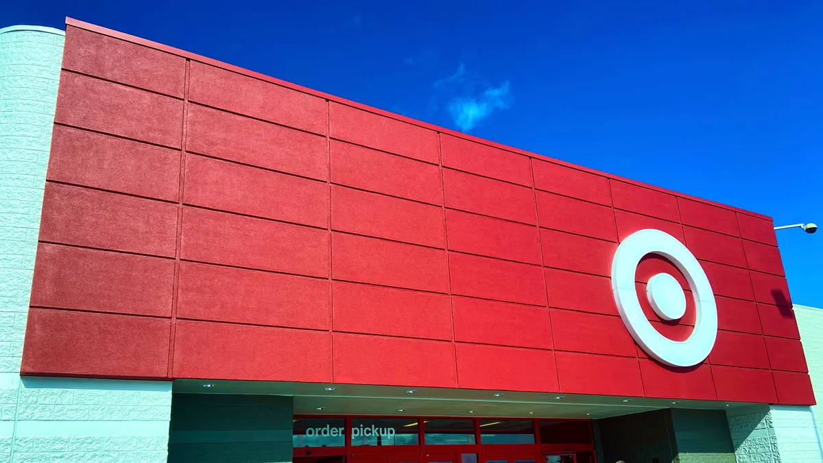 A bright red store banner with a white Target logo, against a bright blue sky with a small cloud puff.