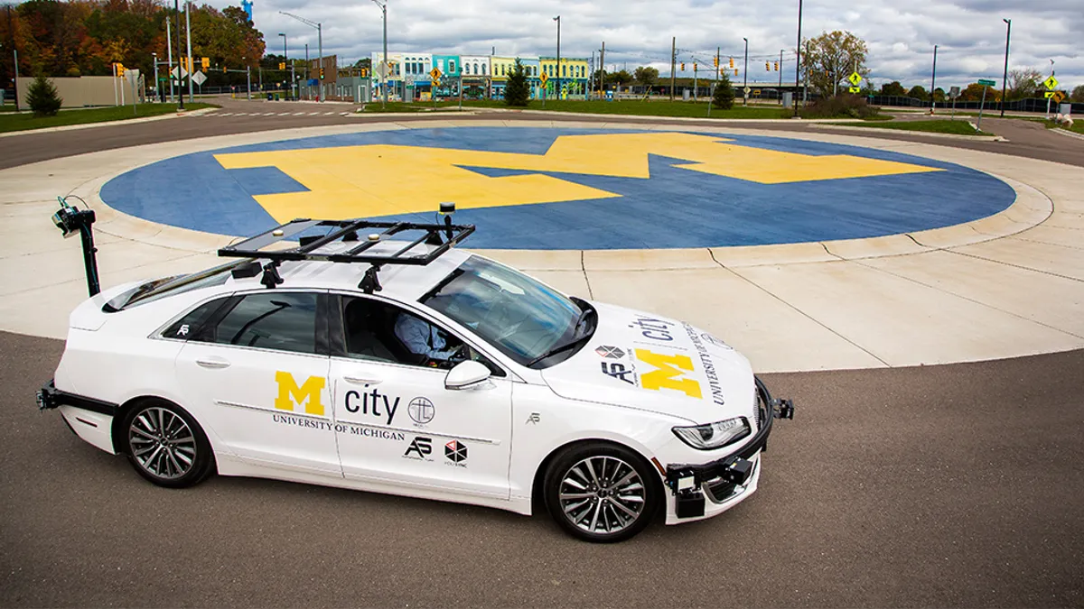 A white Lincoln MKZ self-driving vehicle is driving around a circle at the University of Michigan test facility.