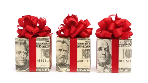 Three cubes of dollar bills wrapped in ribbons, resembling unopened presents.