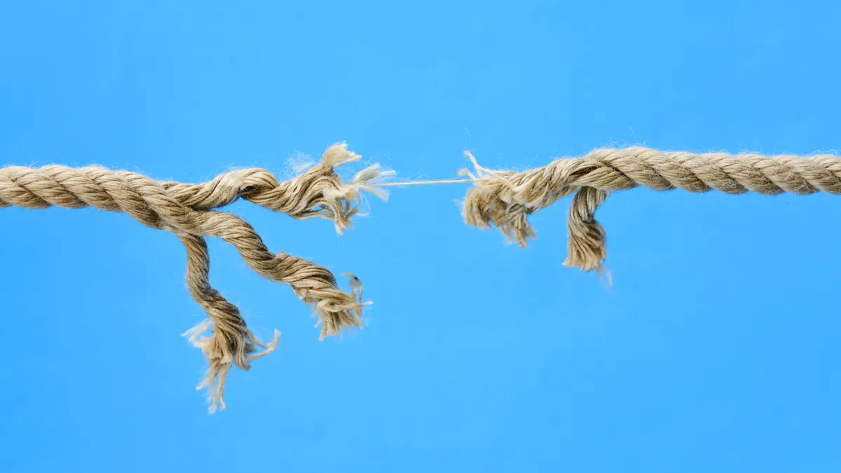 Frayed rope breaking on blue background