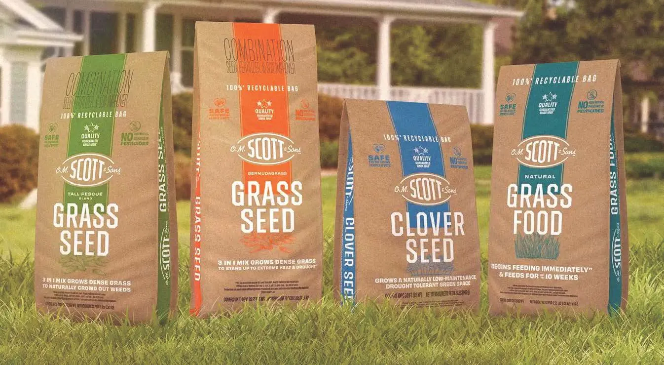 Four bags of ScottsMiracle-Gro lawn care products in paper bags.