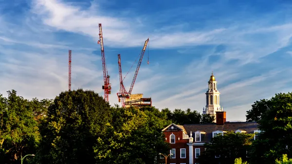 Construction cranes are visible over trees, as well as Harvard Business School.