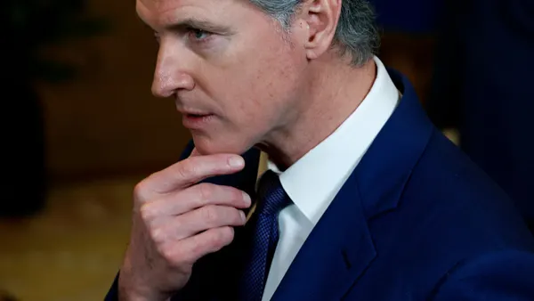 California Gov. Gavin Newsom in a suit holding his hand to his chin.
