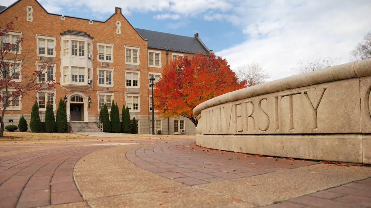 A college campus with a building in the background during fall.