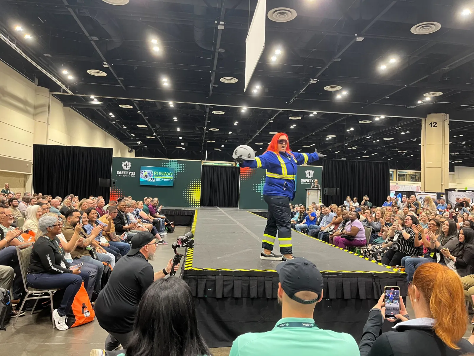 A model spreads her arms in safety gear at the end of a catwalk.