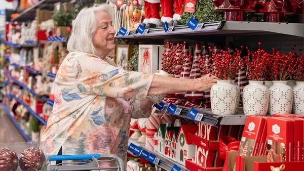 A person with white hair shopping for red and green holiday decorations in store