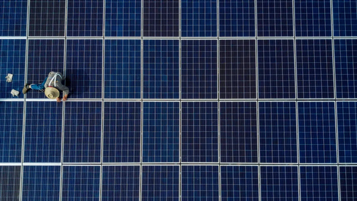 A Chinese worker from Wuhan Guangsheng Photovoltaic Company works on a solar panel project on the roof of a 47 story building in a new development on May 15, 2017 in Wuhan, China.