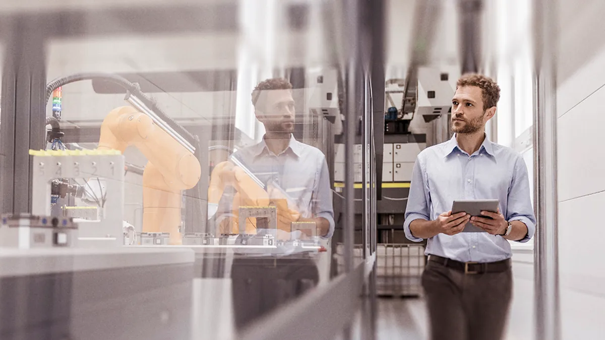 A person holding a tablet and walking through a manufacturing warehouse