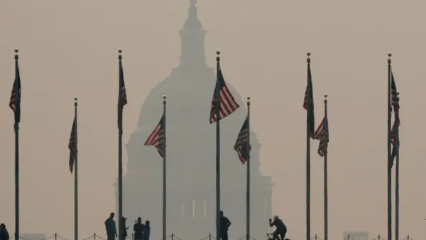 Tourists walk around the base of the Washington Monument amid smoky air.