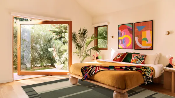 Display of a striped green Ruggable x Monica Ahanonu rug under a bed