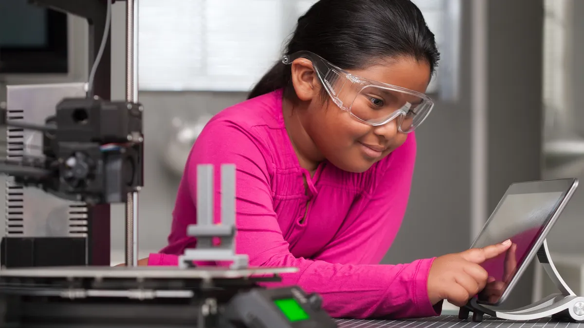 A young student sits in front of a computer screen.