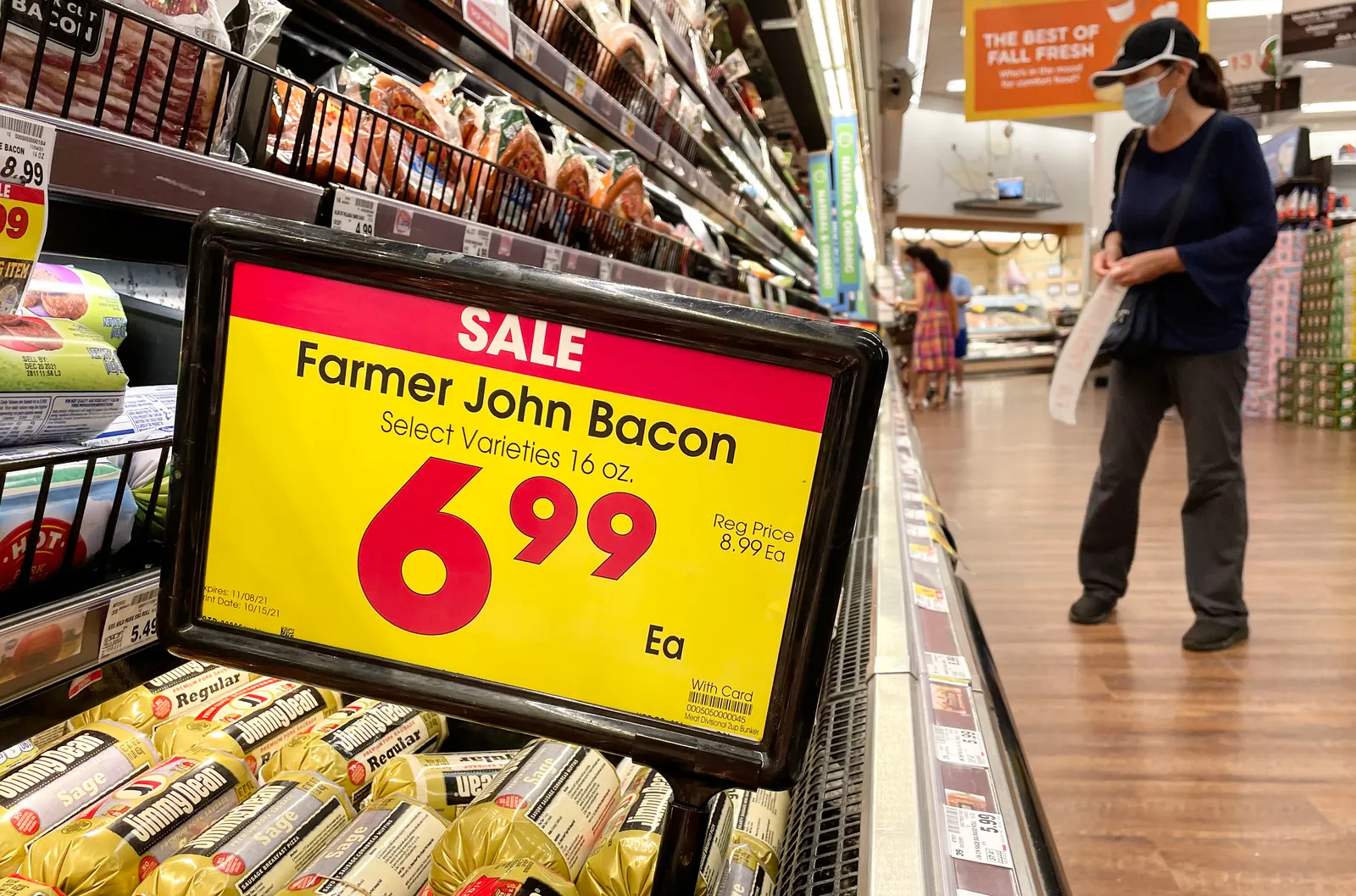 A person shops in the meat section of a grocery store.