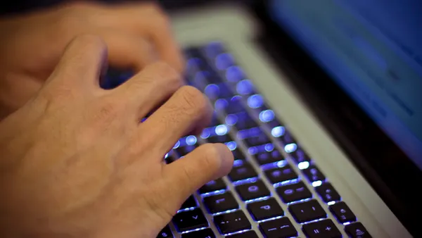 Hands type on a laptop keyboard