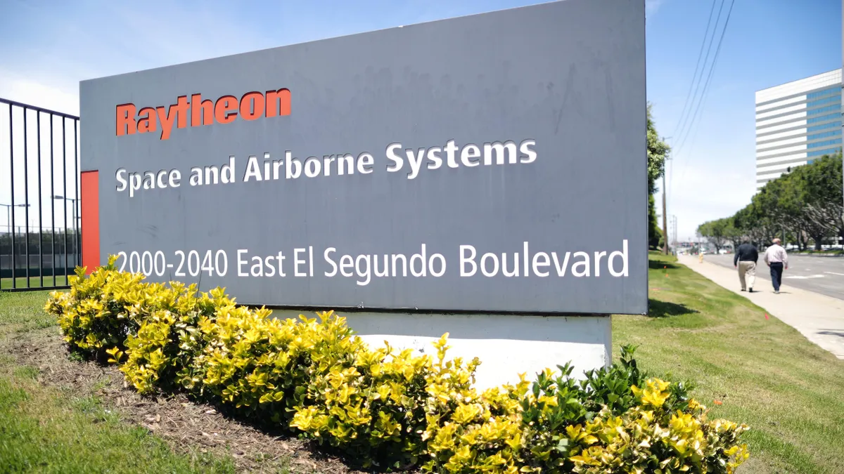 Raytheon campus sign with some shrubbery in the foreground.