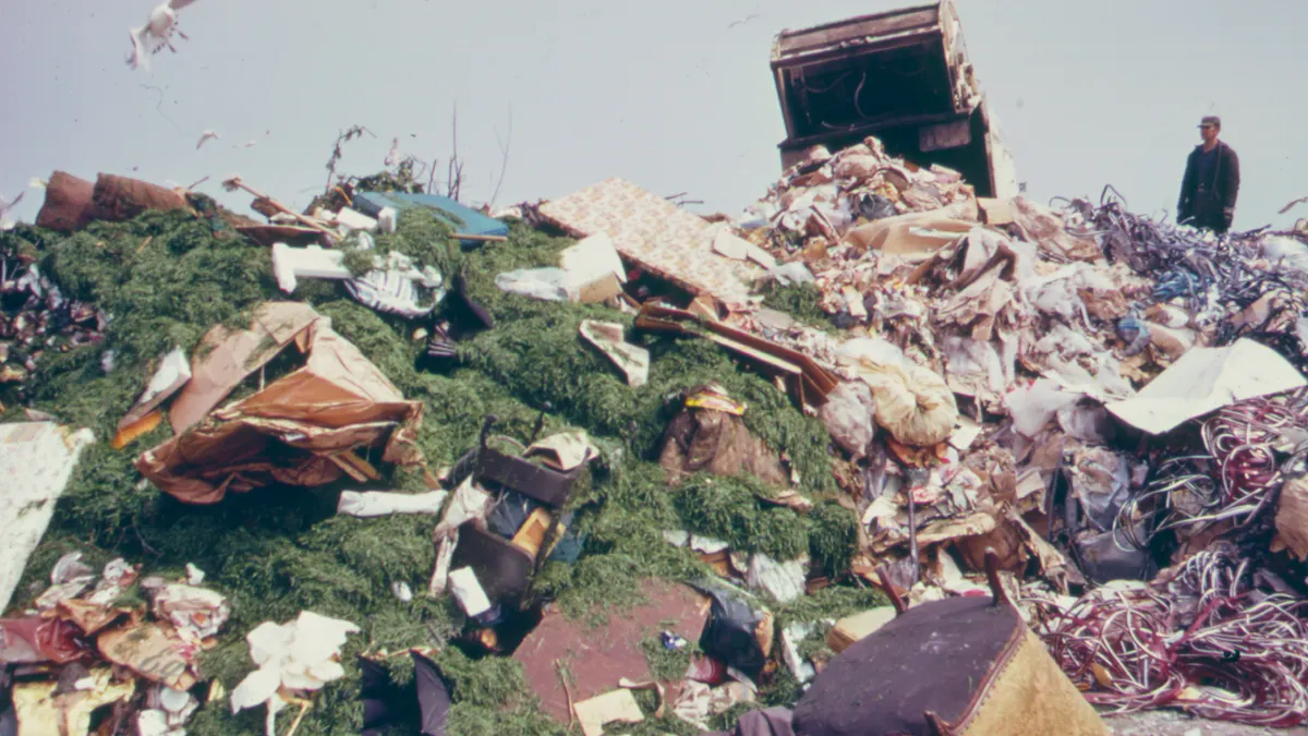 A large pile of waste dumped, with man and truck in background