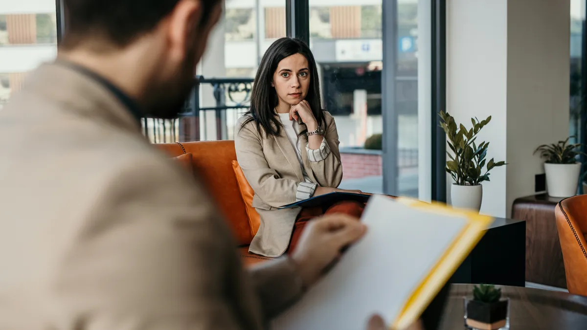 Worried person with guarded body language thinks of something while having a job interview at the corporate office