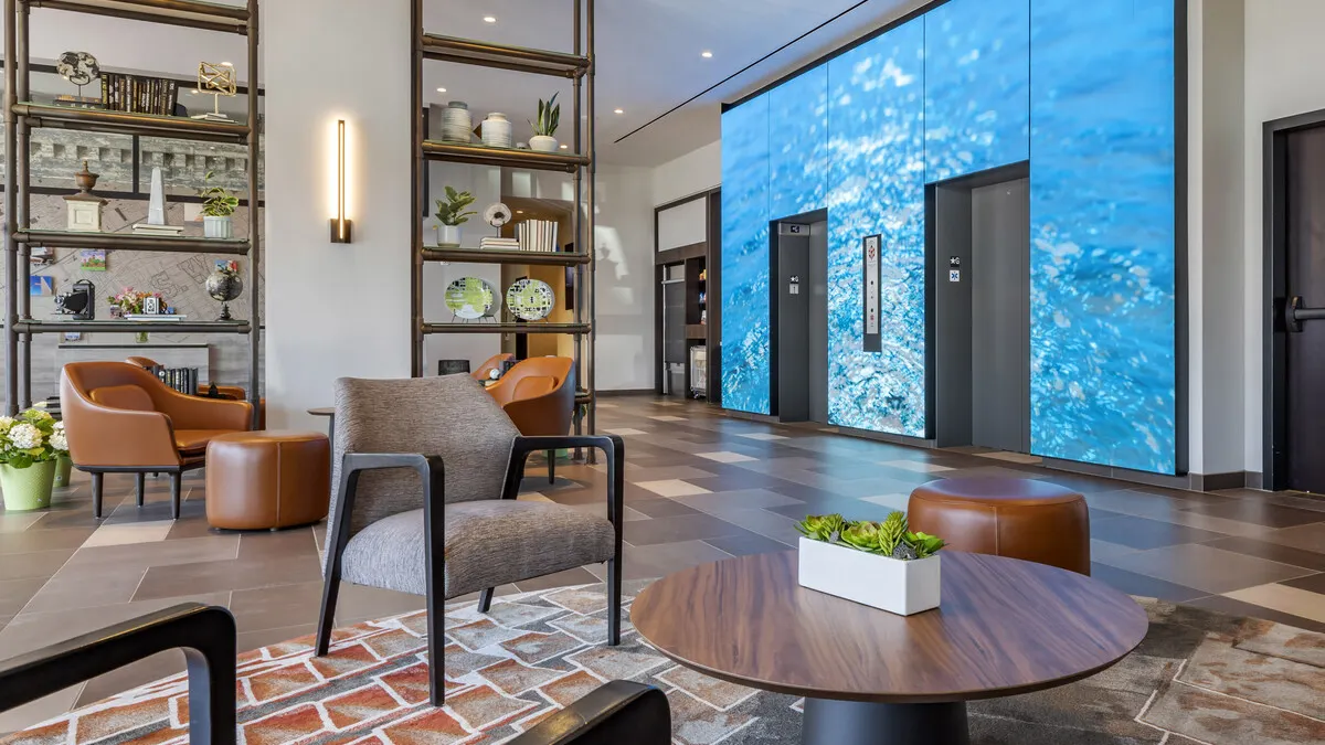 The lobby of a hotel features chairs and elevators.
