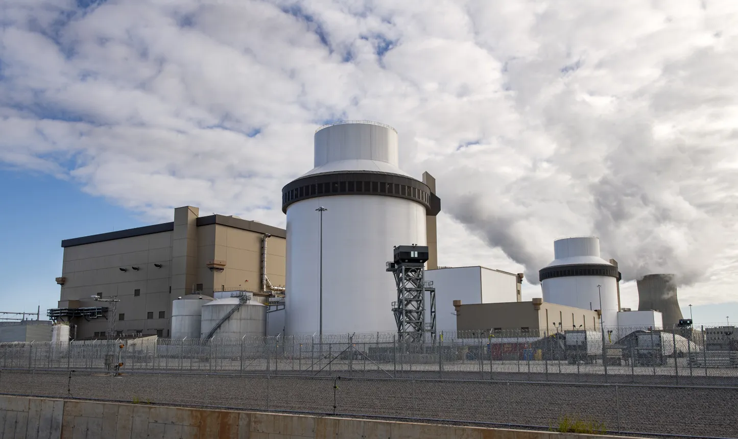 Two tall white industrial structures stand among an array of buildings.