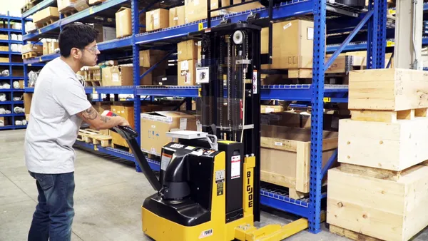 Man using stacker machine to lift boxes