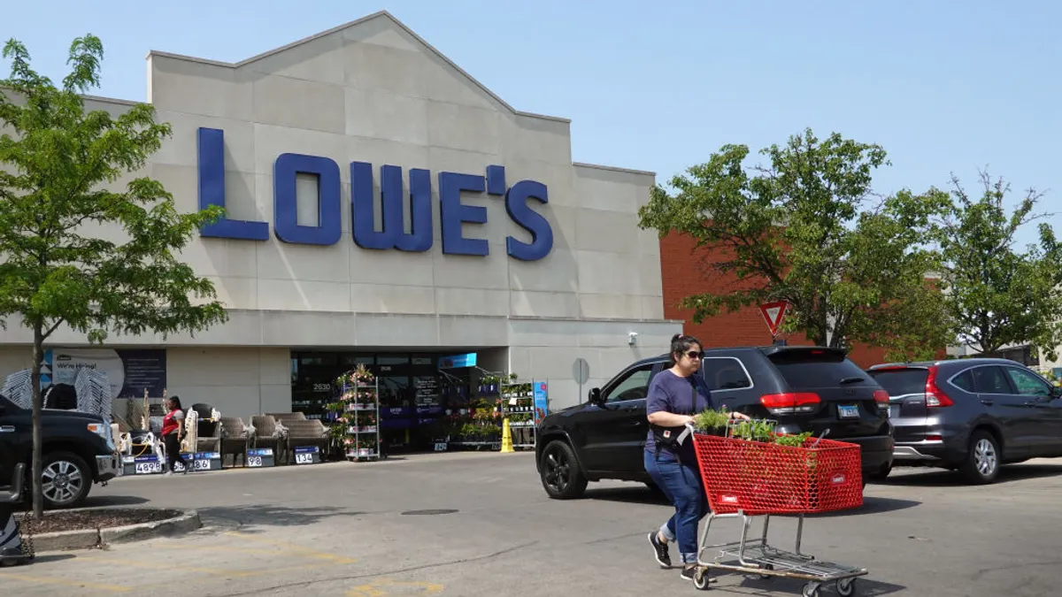 A customer pushes a cart outside a Lowe's store.
