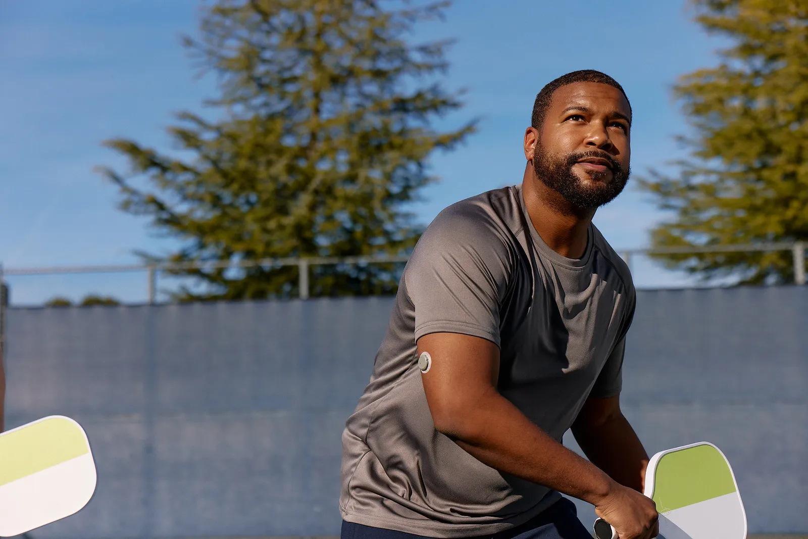 A person playing pickleball wears a circular patch on their upper arm.