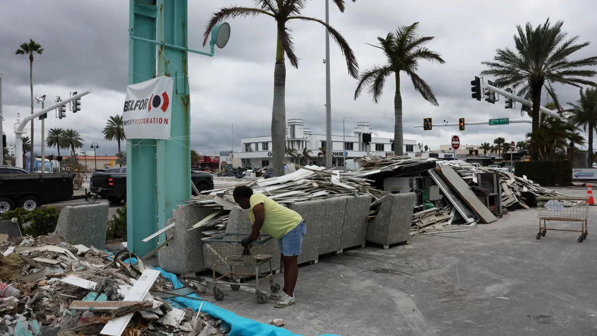 A person cleans debris from a hurricane in a street