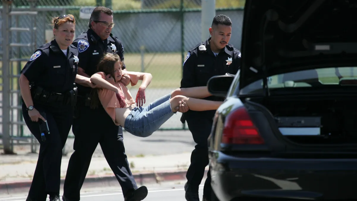 Three policeman carry a student