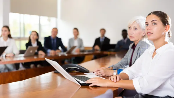 Millennial white brunette businesswoman attending presentation