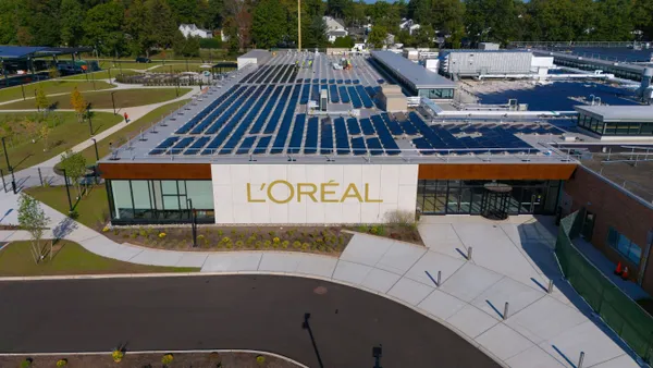 An overhead view of a one-floor building with a large white and gold L'Oréal sign between glass windows.