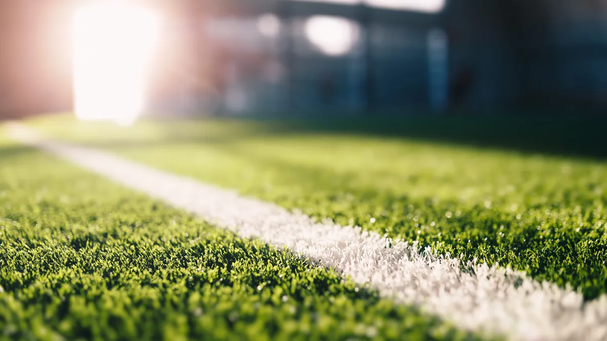 A close up of sideline on a soccer field, with sunlight in the background.