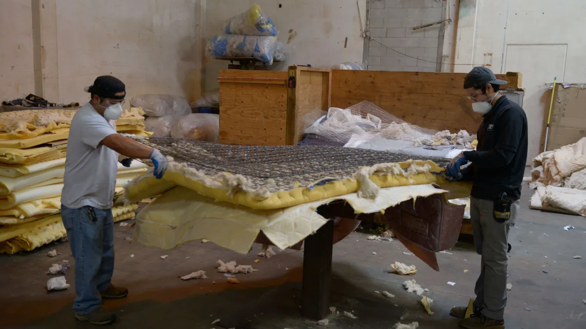 a worker disassembles a mattress in a warehouse filled with mattresses