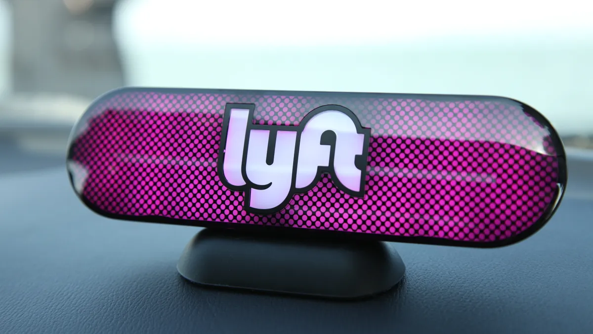 A photo of a Lyft logo on a car's dashboard.