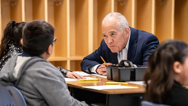 Houston Independent School District Superintendent Mike Miles sits at a table with younger students