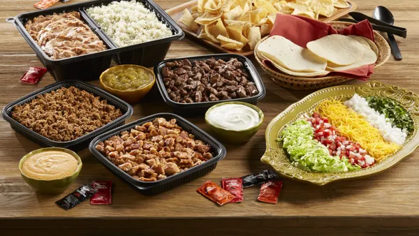 A promotional image for Del Taco's catering program. Bowls of Mexican fast food on a table.