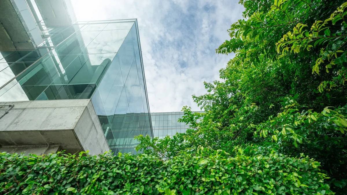 A modern office with glass windows looking over a green outdoor courtyard.