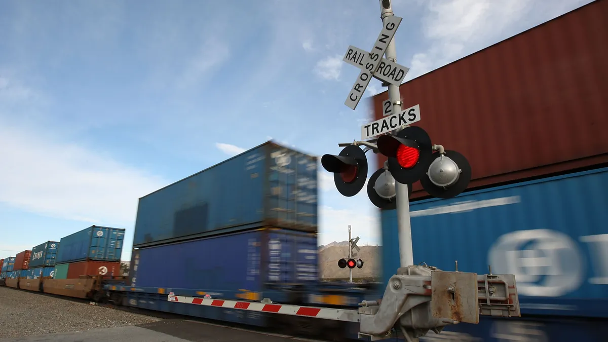 Boxes on a train zoom past a railroad crossroad