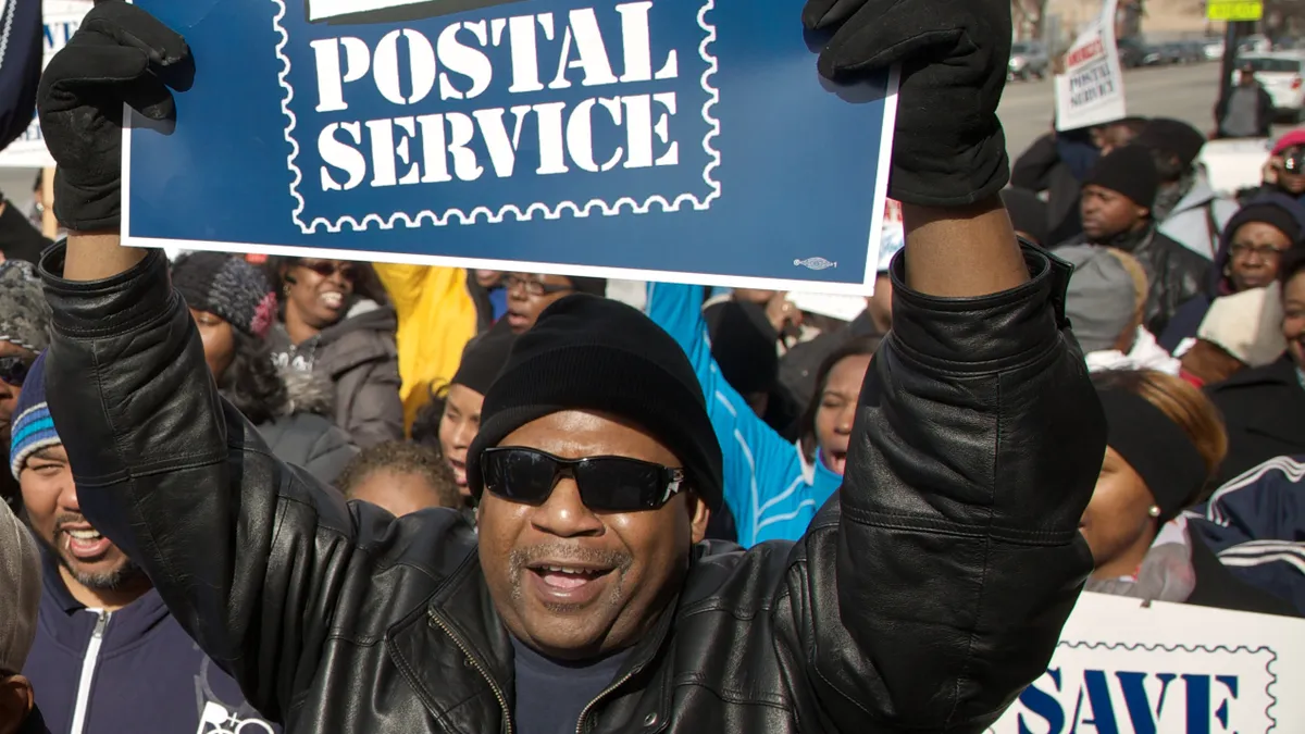 Outside a post office in Chicago, Illinois, a postal worker protests against the USPS' announcement of a plan to end Saturday mail delivery.