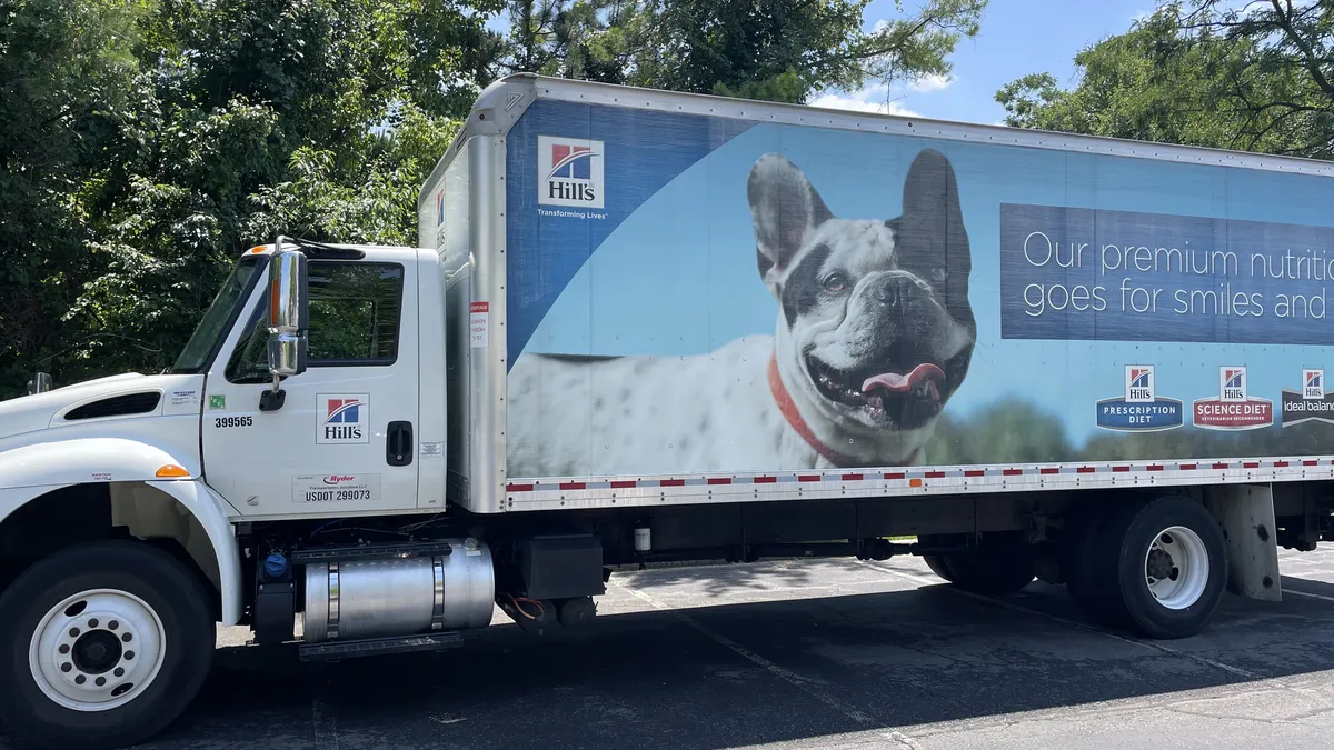 A Hill's pet food truck with trees behind it.