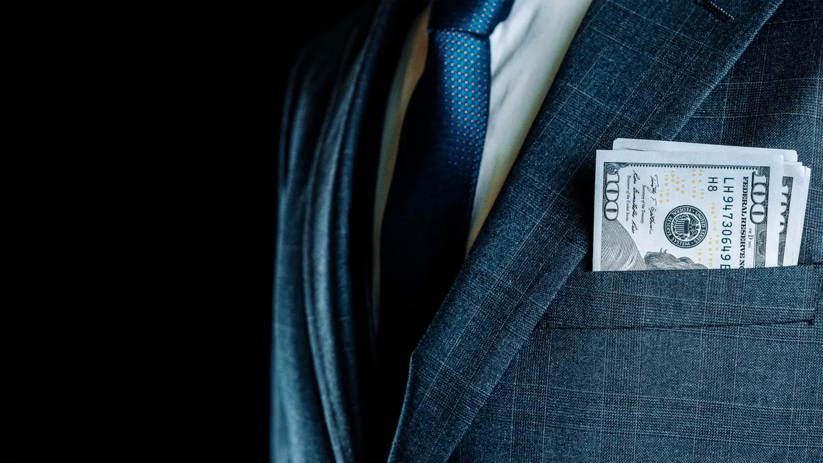 Businessman with one-hundred-dollar bills in his breast pocket