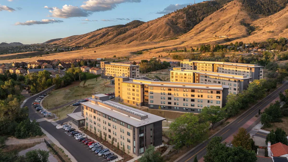 Aerial picture of a tan apartment community with mountains in the background.