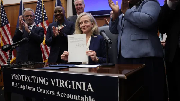 Virginia Gov. Abigail Spanberger holds up a document with her signature